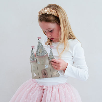 girl wearing a gold sequin headband and castle bag against a white background