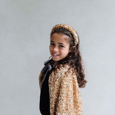 girl wearing a gold sequin headband against a white background