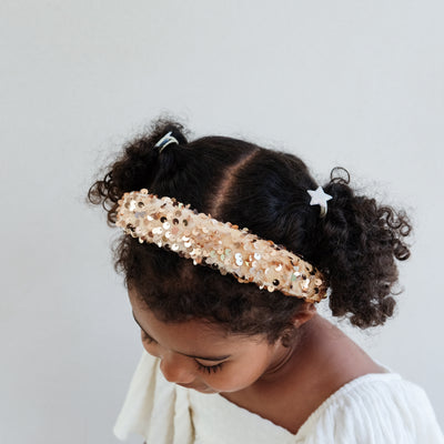 girl wearing a gold sequin headband against a white background