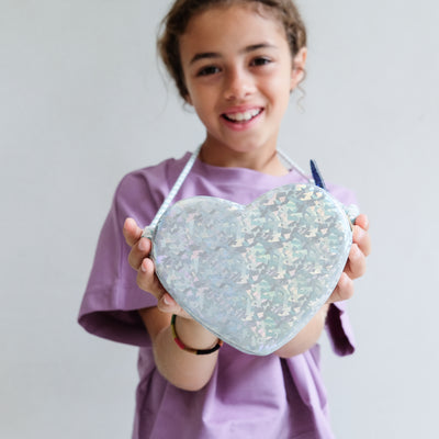 Child holding a heart-shaped bag against a plain background