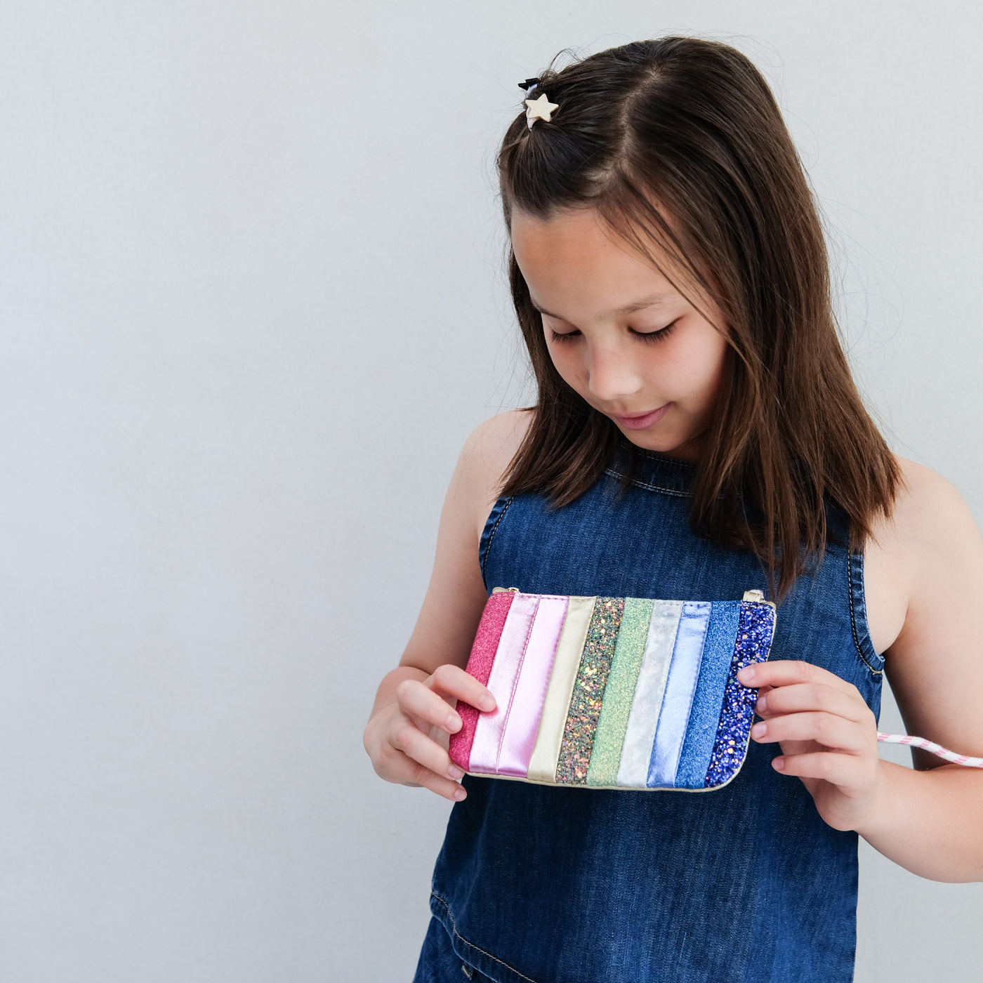 Young girl holding a colourful striped bag against a plain background