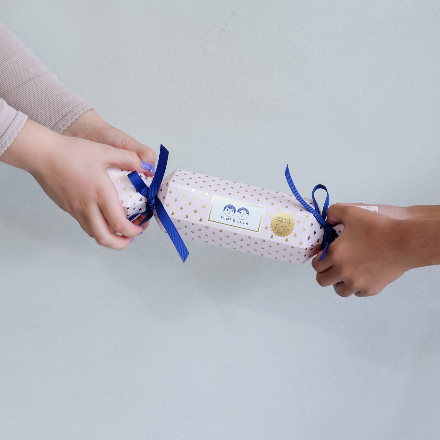 two hands holding a Christmas cracker gift box against a white background