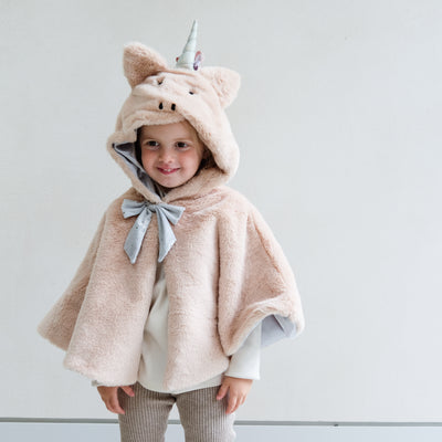 girl wearing faux fur unicorn dress up cape against a white background