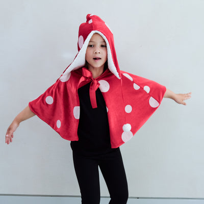 girl wearing a toadstool dressing up red cape, and matching hat against a white background