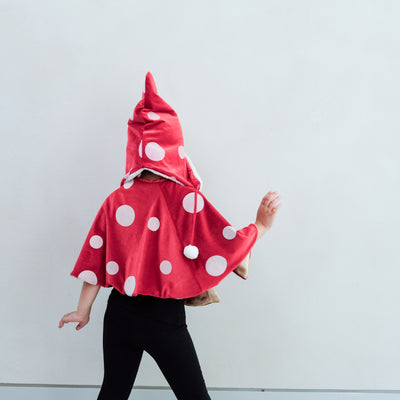 girl wearing a toadstool dressing up red cape, and matching hat against a white background