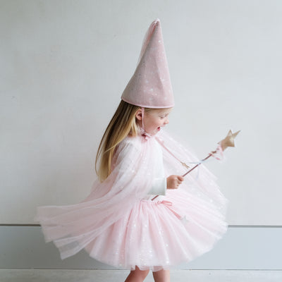 Child wearing a shimmer pink tutu, cape, and matching princess crown costume with a white background