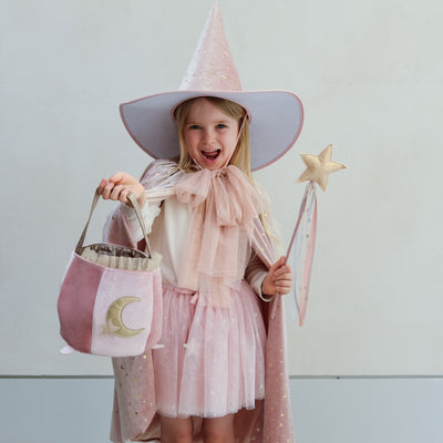 girl wearing glinda pink witch costume holding a pink cauldron trick or treat bag