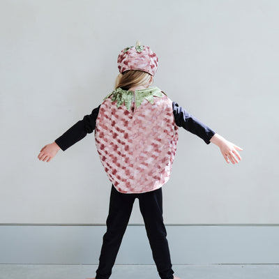 Child wearing a patterned pumpkin costume with matching hat against a plain background