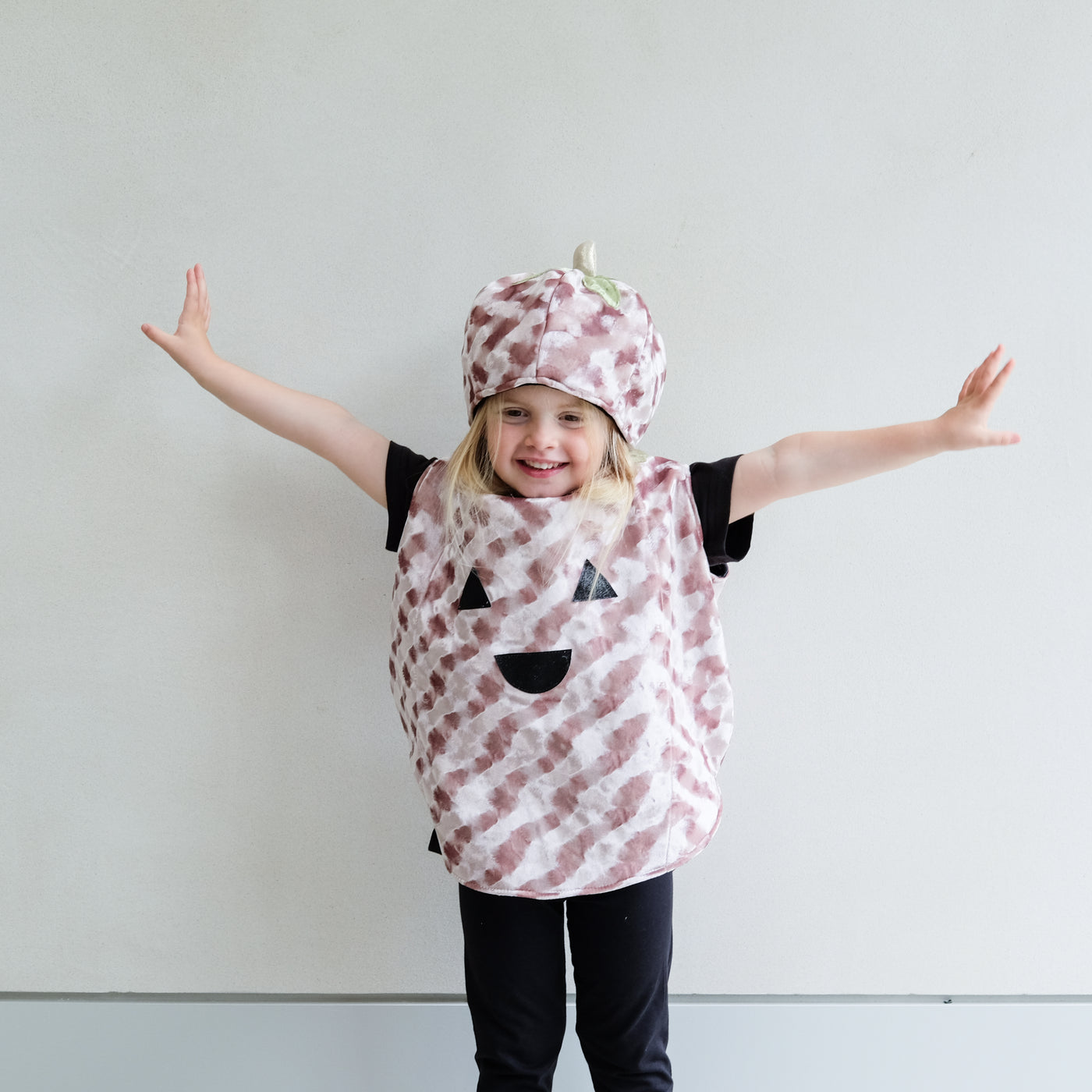 Child wearing a pumpkin costume with black accents against a plain background