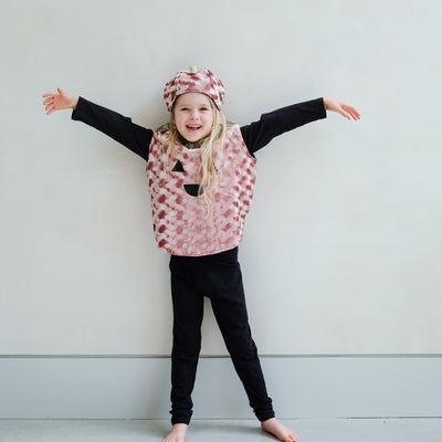 Child wearing a pumpkin outfit with black sleeves and trousers, standing against a plain background.