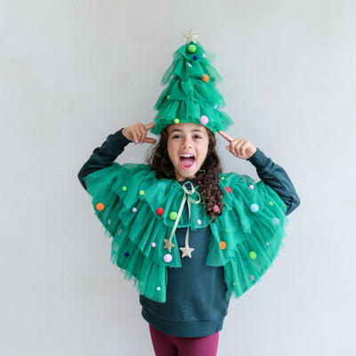 Person wearing a Christmas Tree costume with tulle and decorations, posing against a plain background.