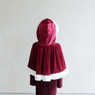Red velvet hooded cape with white trim on a plain background