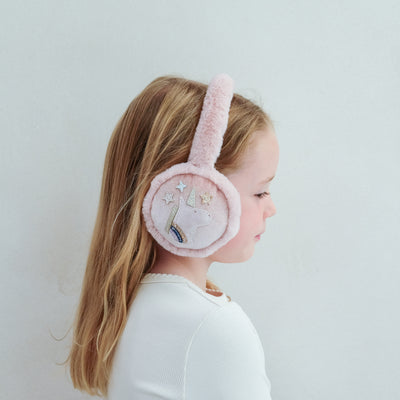 Child wearing pink earmuffs with unicorn and star designs on a plain background