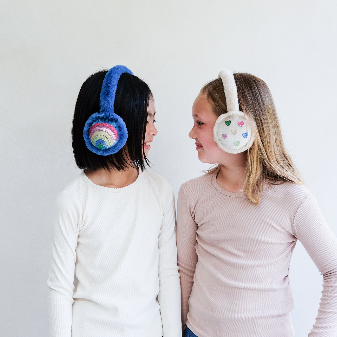 Two children wearing colourful earmuffs against a white background