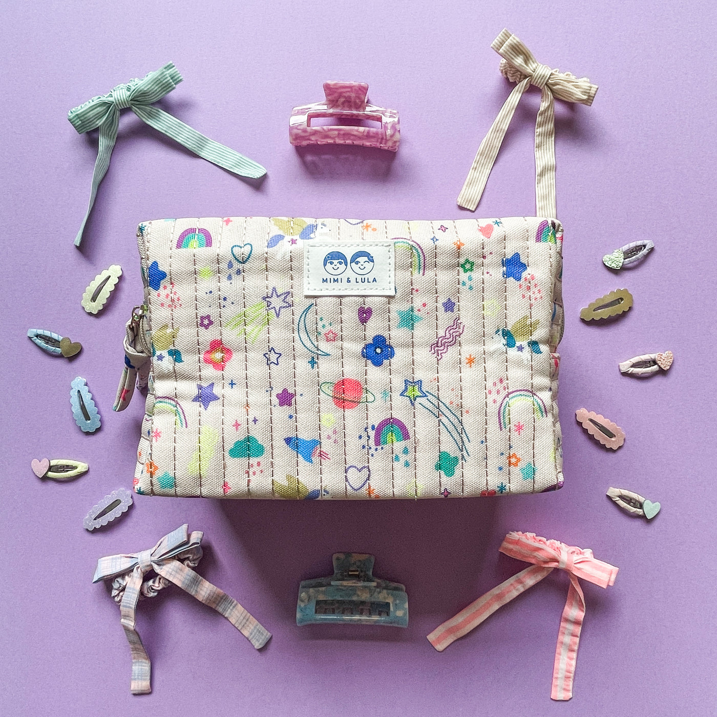 Wash bag in unicorn print fabric surrounded by hair clips and bow scrunchies