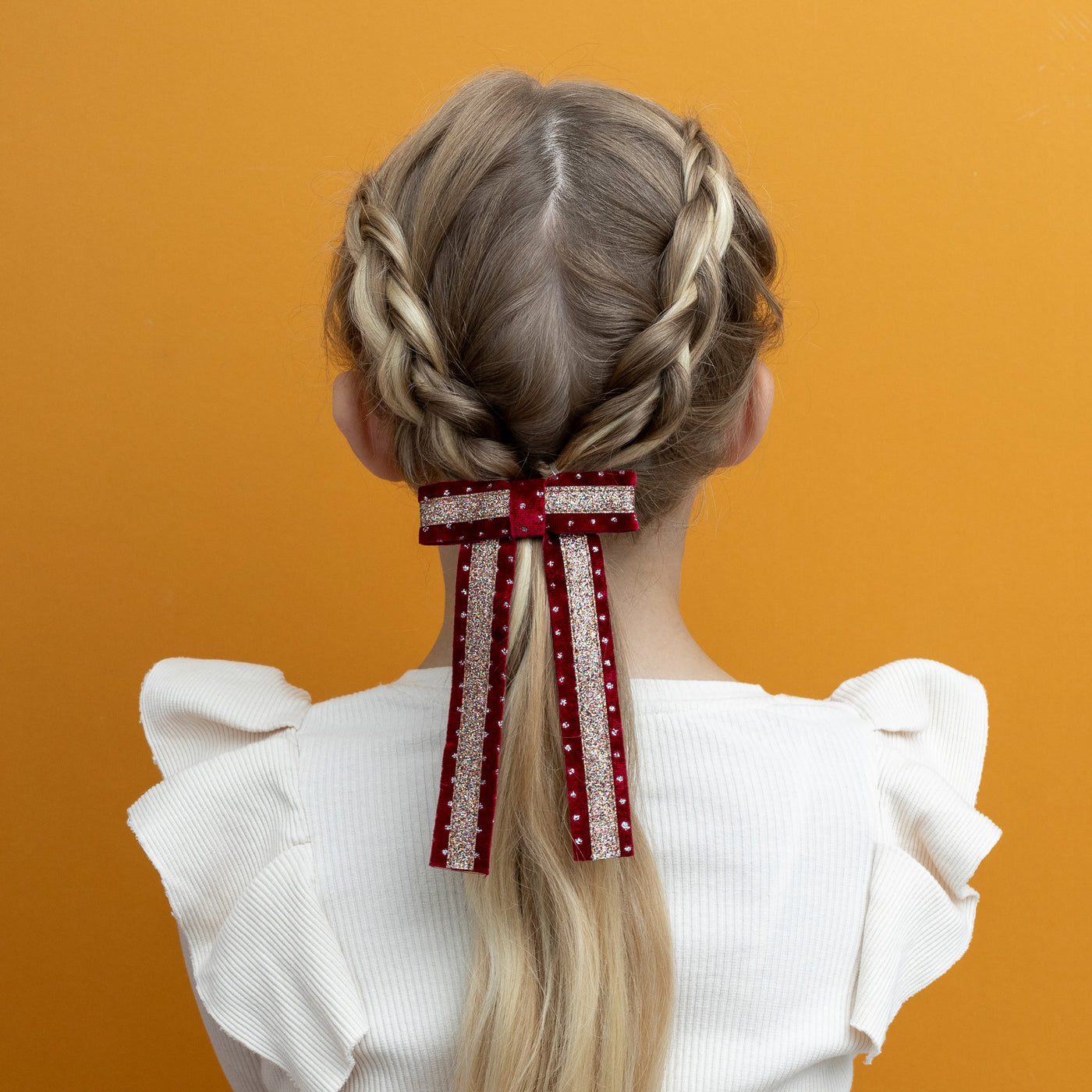 Long light hair decorated with red and gold circus bow hair clip in velvet