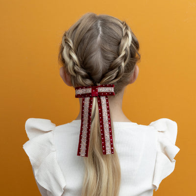 Long light hair decorated with red and gold circus bow hair clip in velvet