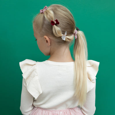 Blonde girl with fancy ponytail decorated with mini velvet bow clips