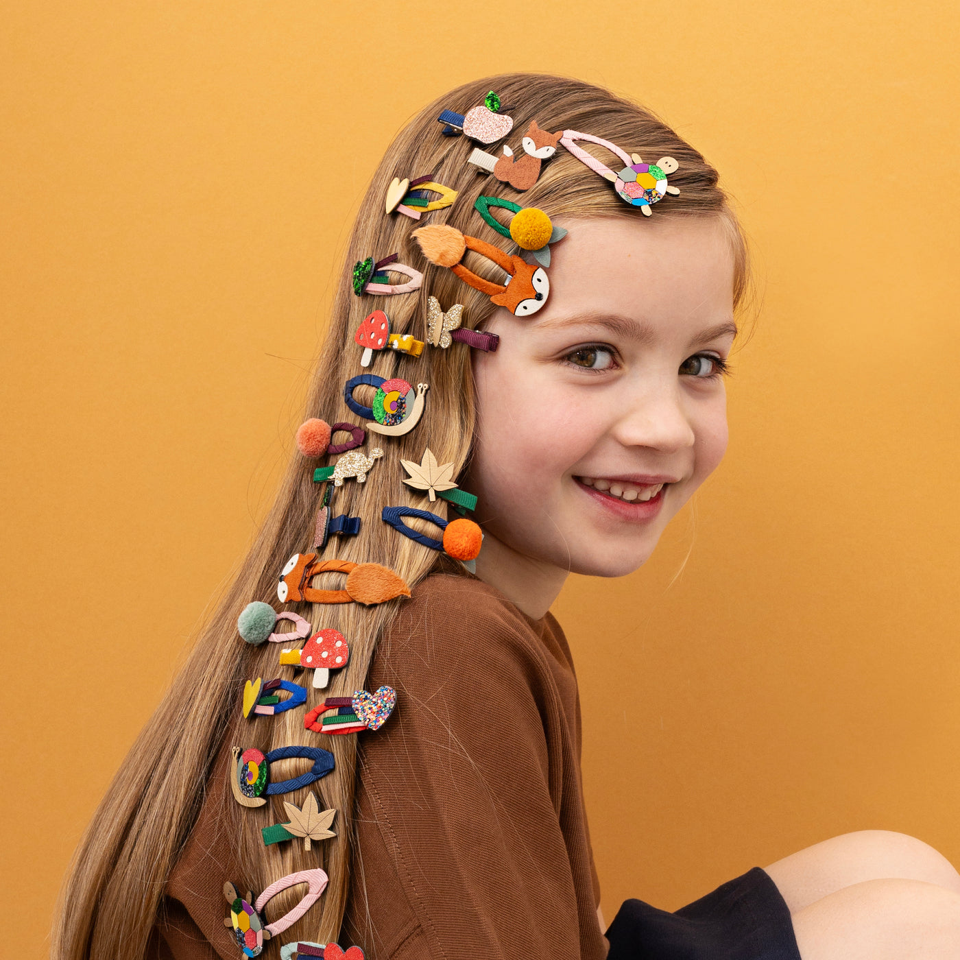 Little girl smiling with lots of autumnal themed hair clips featuring little animals