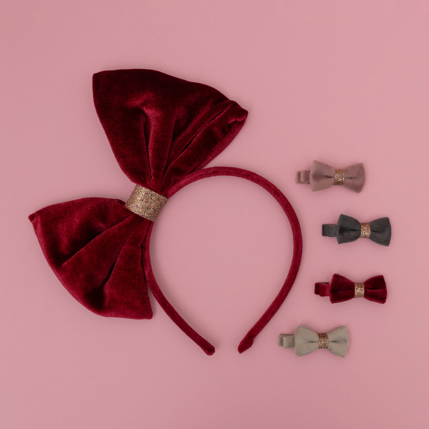 Large oversize red velvet bow alice band on pink background with four velvet bow mini hair clips