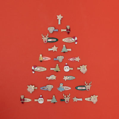 Beautiful assortment of children's mini hair clips placed on a red background in the shape of a Christmas tree, featuring nutcrackers, mice, reindeer, ballerinas, stars, santas, trees and candy canes