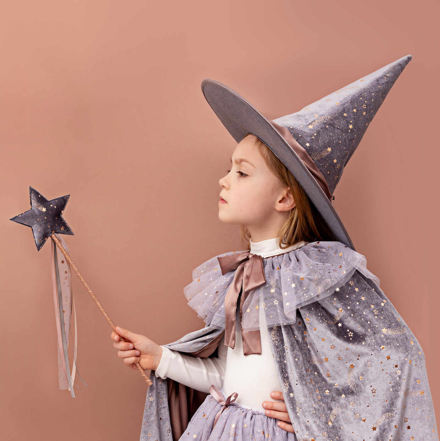 Little girl dressed up as a witch wearing a beautiful star speckled grey velvet set including a ruffle collar cape, large brim pointed hat, matching grey tutu and holding a matching velvet star wand