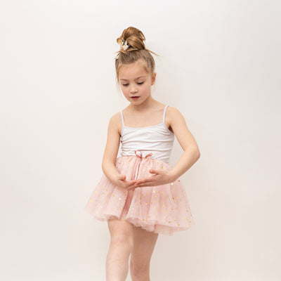 Little girls wearing a soft pink tulle star speckled tutu with hair tied up in a bun