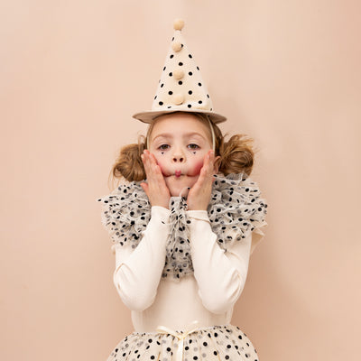 Little girl pulling funny face wearing polka dot clown fancy dress set 