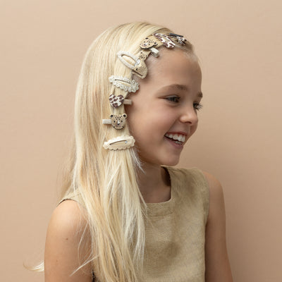 Blonde girl smiling wearing multiple leopard and gold theme hair clips all down one side