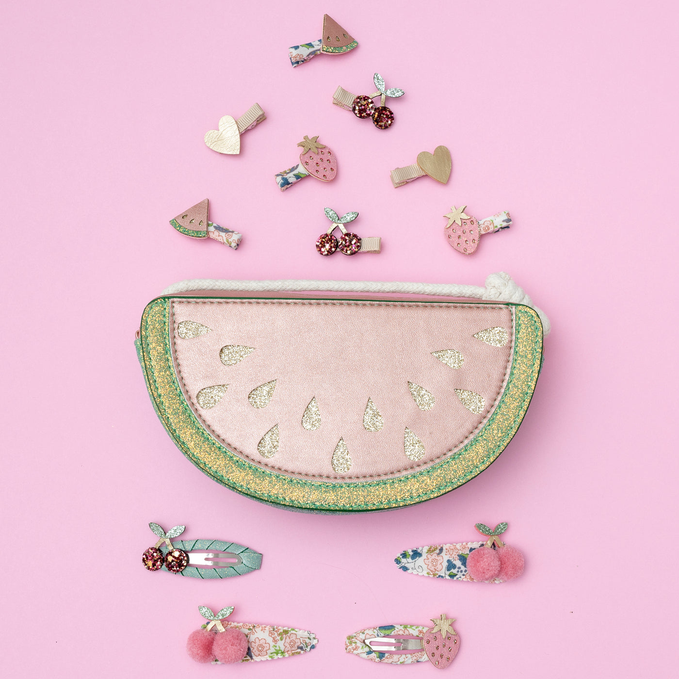 Watermelon bag laid on pink background with fruit hair clips surrounding