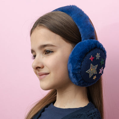 Dark haired little girl wearing Night sky navy earmuffs with twinkly fabric stars and soft, fluffy padding to keep little ears warm and cosy
