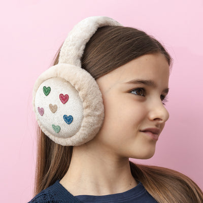Dark haired girl on pink background wearing Jazzy heart earmuffs with glitter fabric hearts and soft, fluffy padding to keep little ears warm and cosy