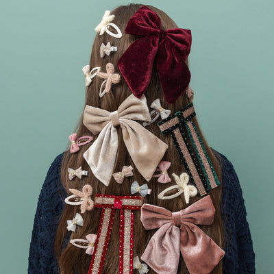Long dark hair decorated with bow hair clips in velvet, glitter and tulle fabrics