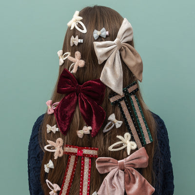 Girl with various decorative hair bows on a plain background