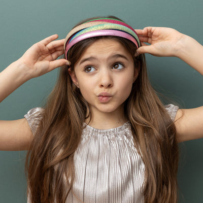 Dark haired little girl pouting wearing five multicoloured alice bands