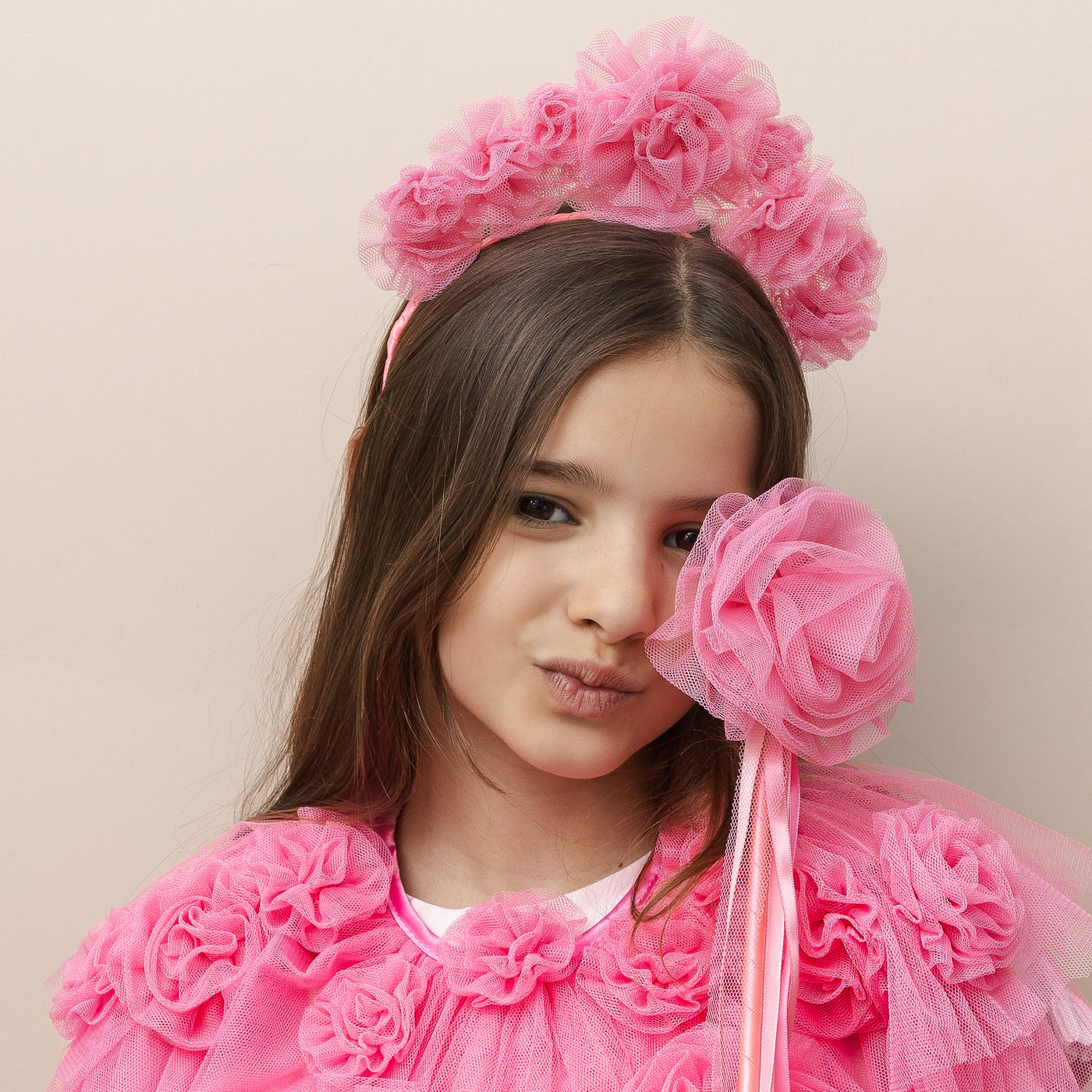 Dark haired little girl wearing a bright pink ruffle flower tulle cape with matching headband and tulle flower wand with ribbons