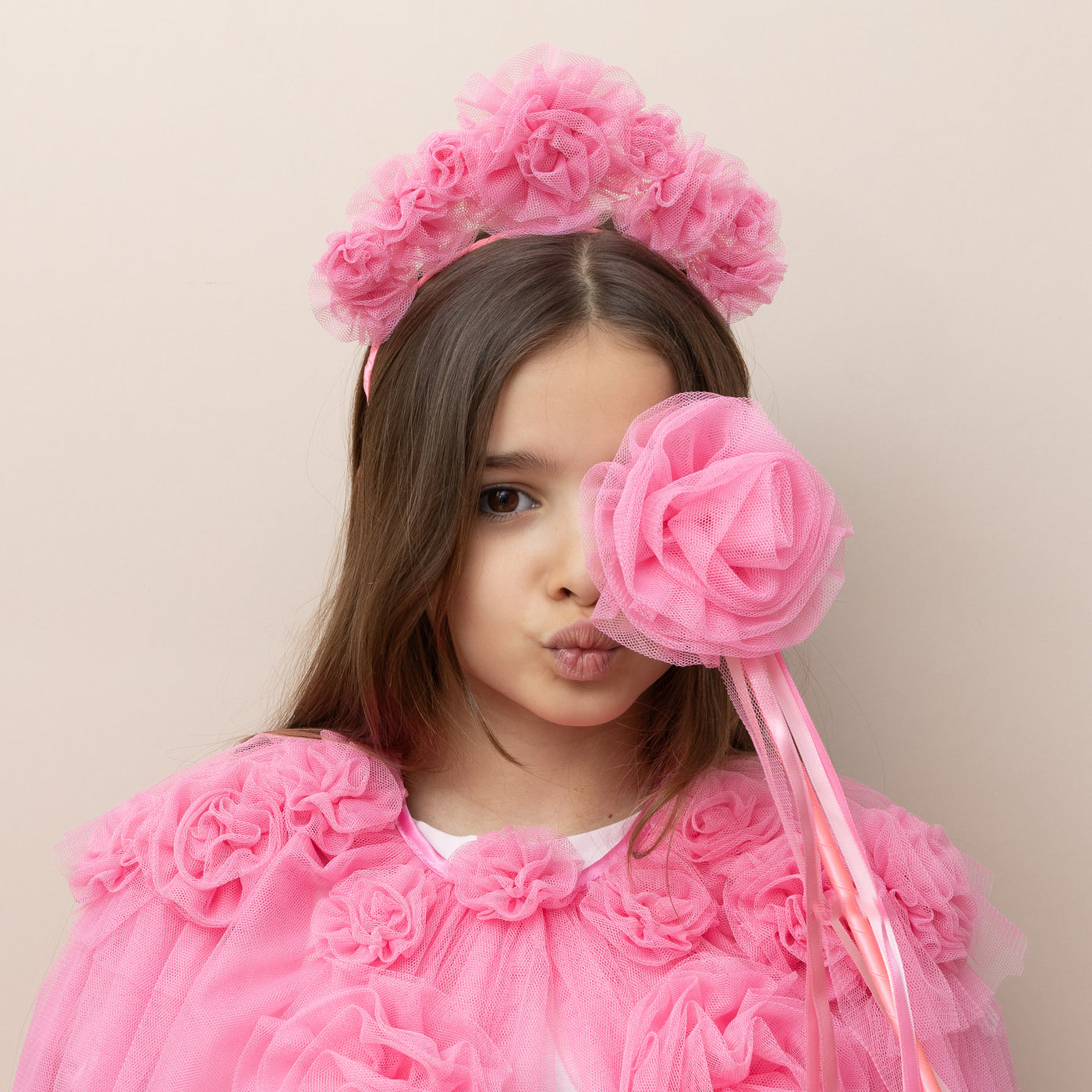 Dark haired little girl wearing a bright pink ruffle flower tulle cape with matching headband and tulle flower wand with ribbons 