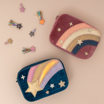 Two rectangular velvet zip top bags with glitter and metallic fabric rainbows and shooting stars plus a selection of star hair clips on a neutral background