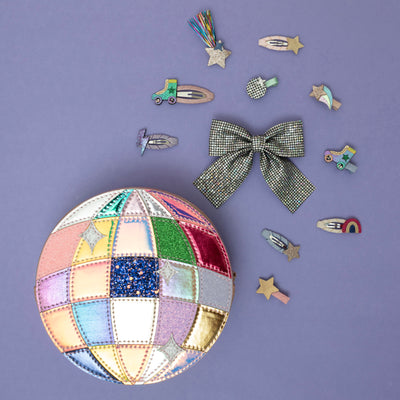 A shimmering pink round disco ball bag, surrounded by a dazzling array of vibrant, party-ready hair accessories, capturing a playful, retro-inspired vibe