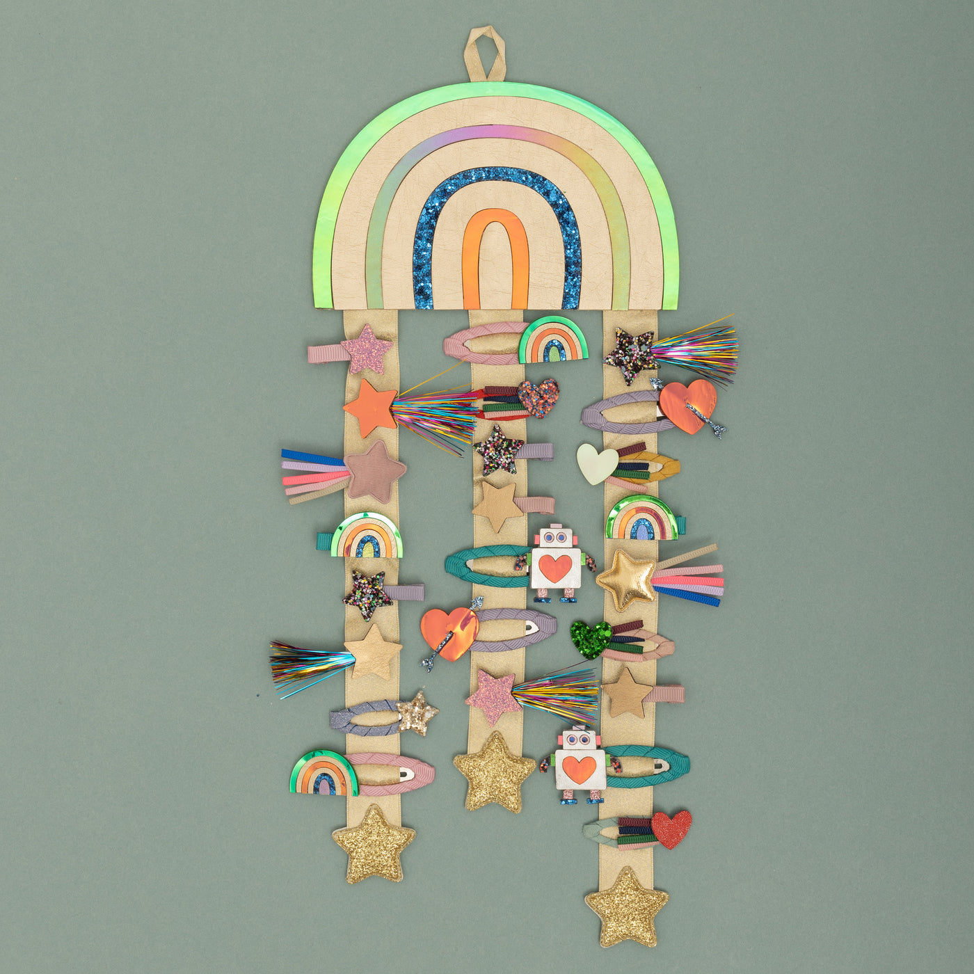 Bright metallic gold hanging rainbow with multicoloured stripes and gold ribbons with gold glitter padded star charms to the ends. Decorated with many different styles of hair clips including stars, hearts, rainbows and robots