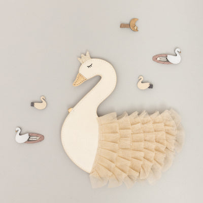 Beautiful swan children's handbag laid on a pale grey background with swan hair clips scattered around