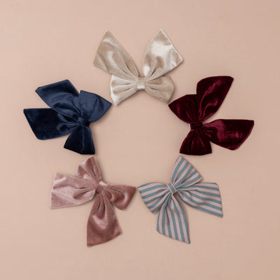 A circle of soft velvet oversized bows in beige, pink, deep red, striped, and navy, creating a charming and elegant arrangement with a mix of rich hues and textures