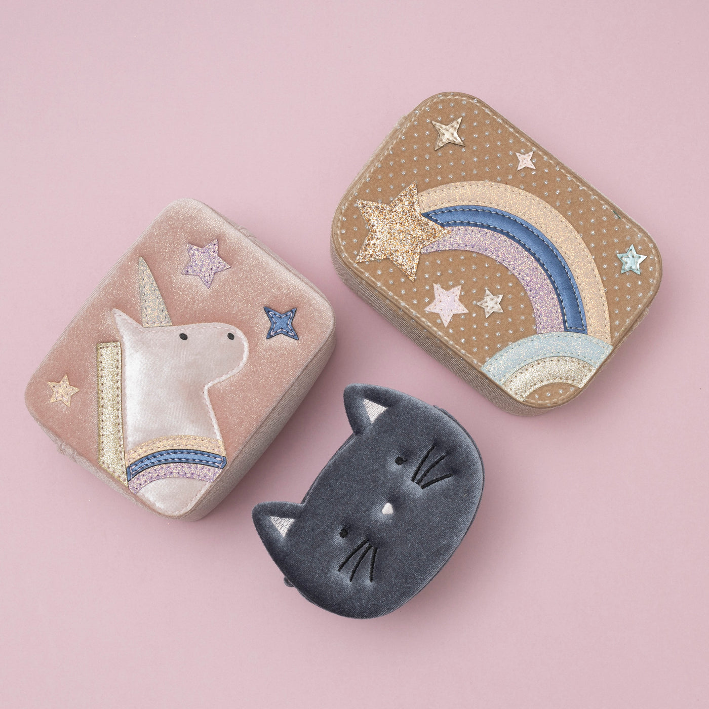 A trio of charming bags: a soft grey velvet kitty cat bag, a blush pink velvet unicorn box bag, and a beige celestial star velvet bag, each showcasing a unique blend of colours and textures, set against a soft pink background