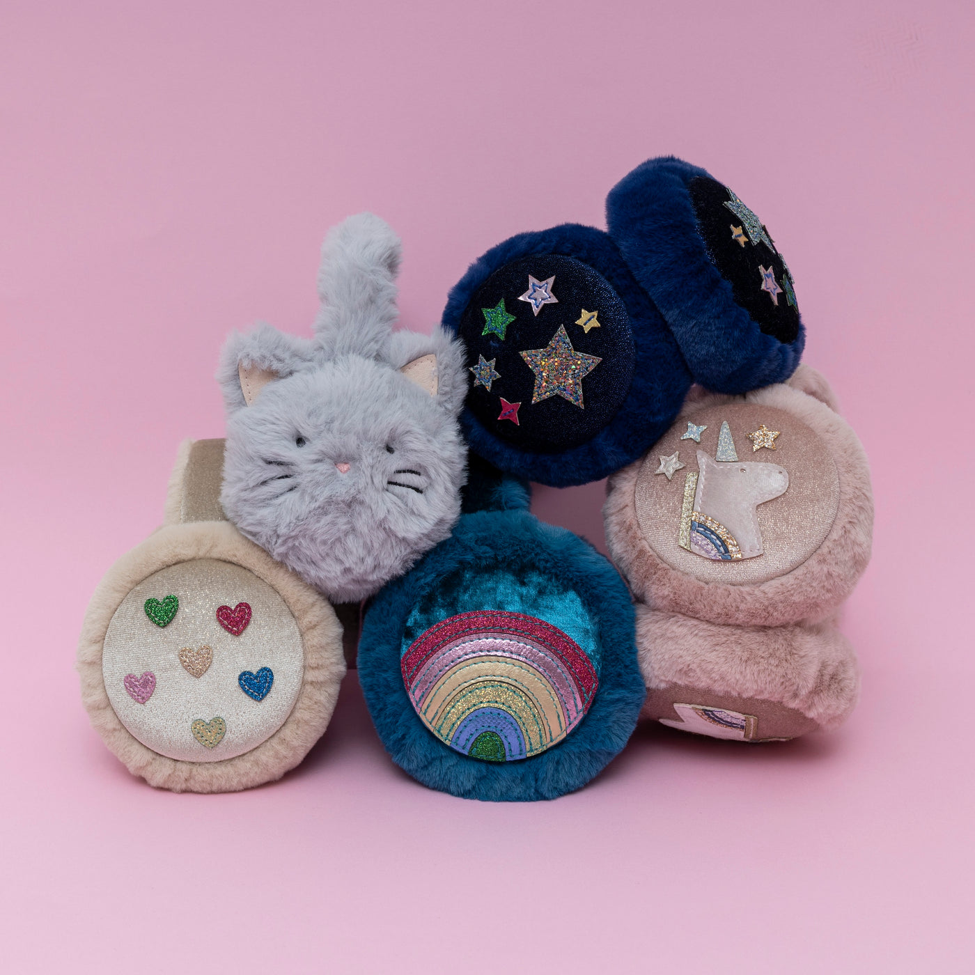 Stack of five fluffy earmuffs in different colours and designs on pink background