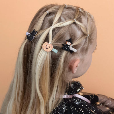 Blonde girl wearing Halloween mini clips on an orange background