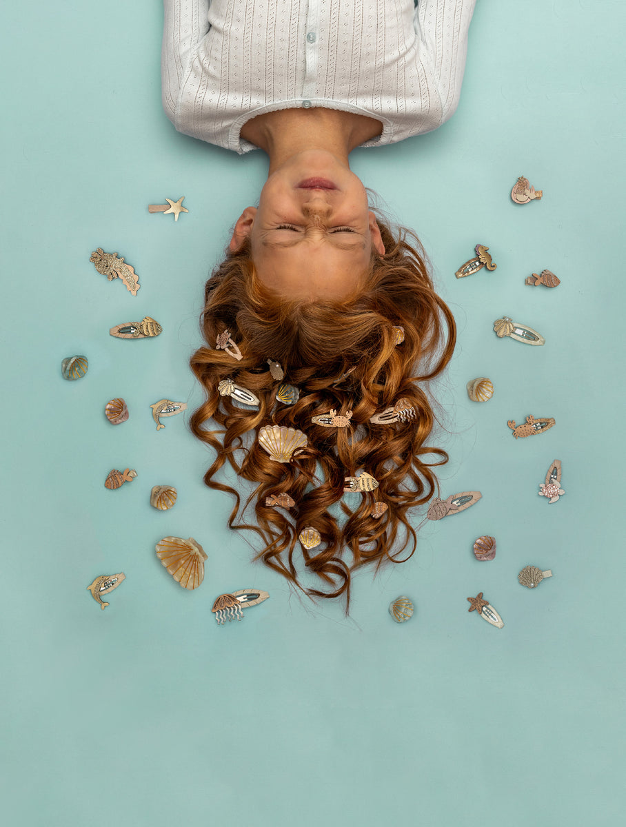 Person with long red hair and decorative hair clips on a light blue background