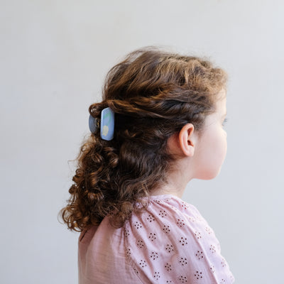 Hair held partly back with a soft blue claw clip with yellow flower print