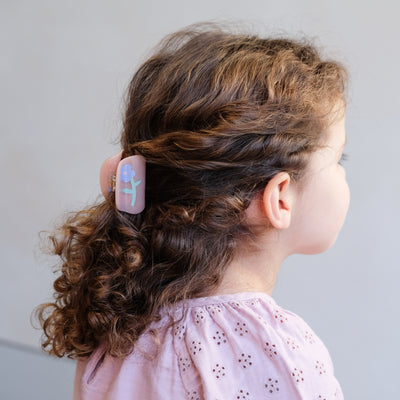 Hair held by a mini, pink hair claw with a purple flower print