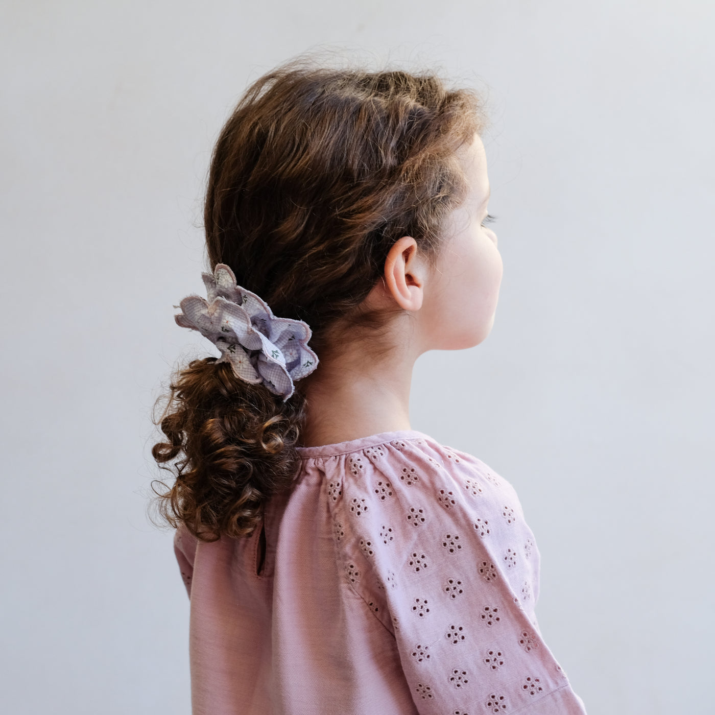 Gingham, floral print double layered scrunchie with scalloped edges worn in a ponytail