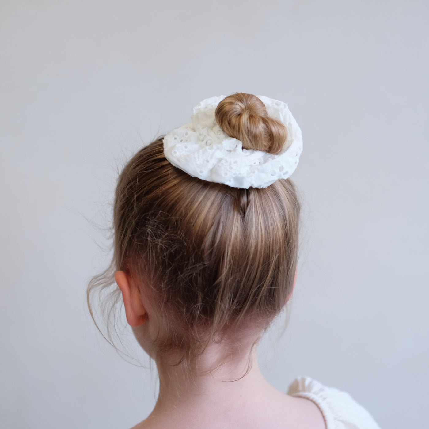 girl wearing giant broderie scrunchie in a bun hair style